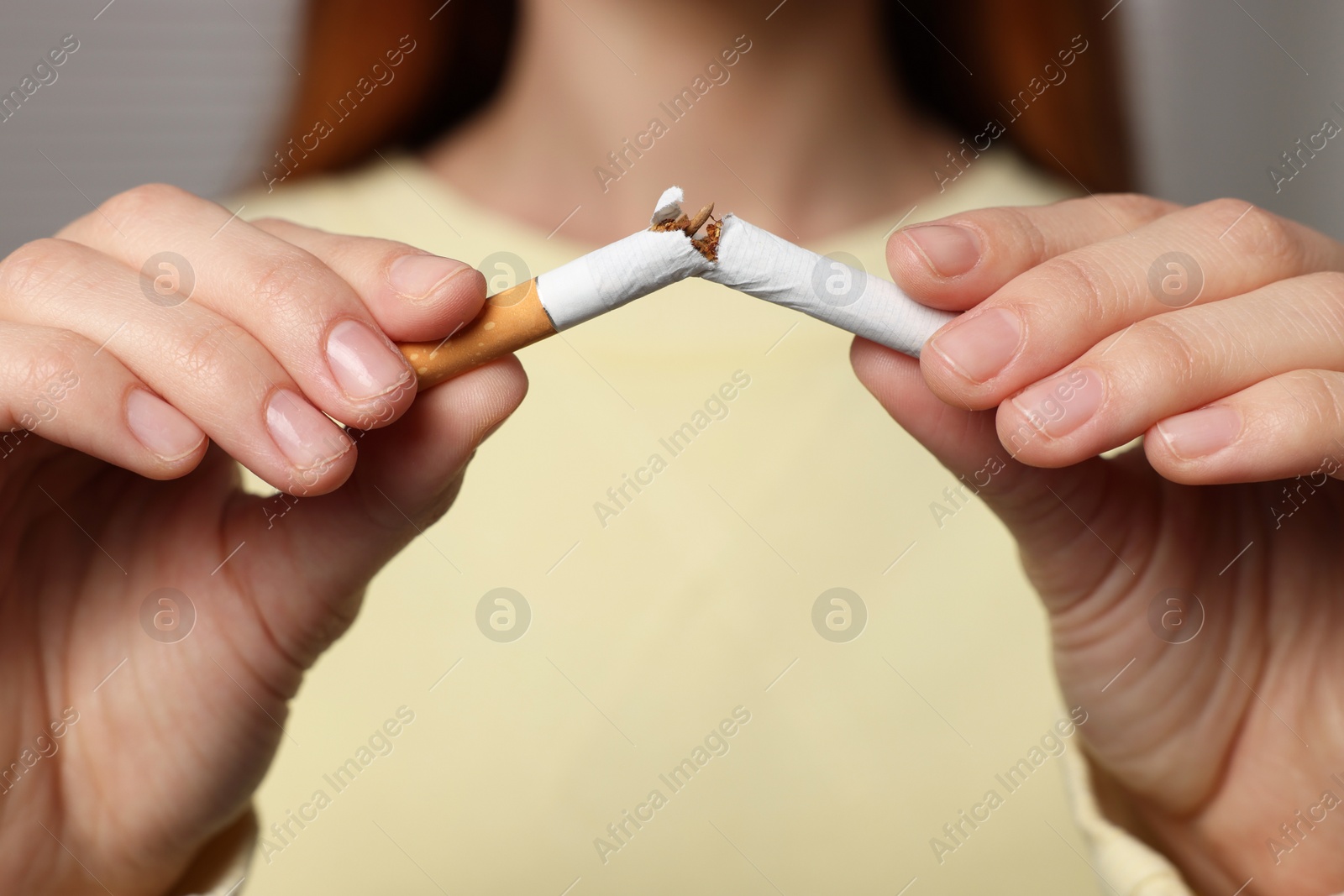 Photo of Stop smoking concept. Woman breaking cigarette on light gray background, closeup