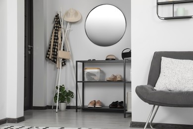 Hallway interior with stylish furniture and round mirror on light wall