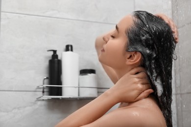 Woman washing hair in shower, space for text