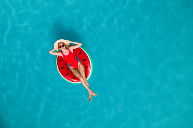 Young happy woman with inflatable ring in swimming pool, top view. Summer vacation