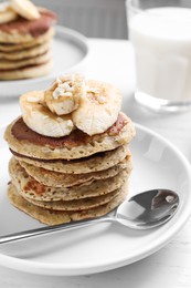 Photo of Plate of banana pancakes served on white wooden table, closeup