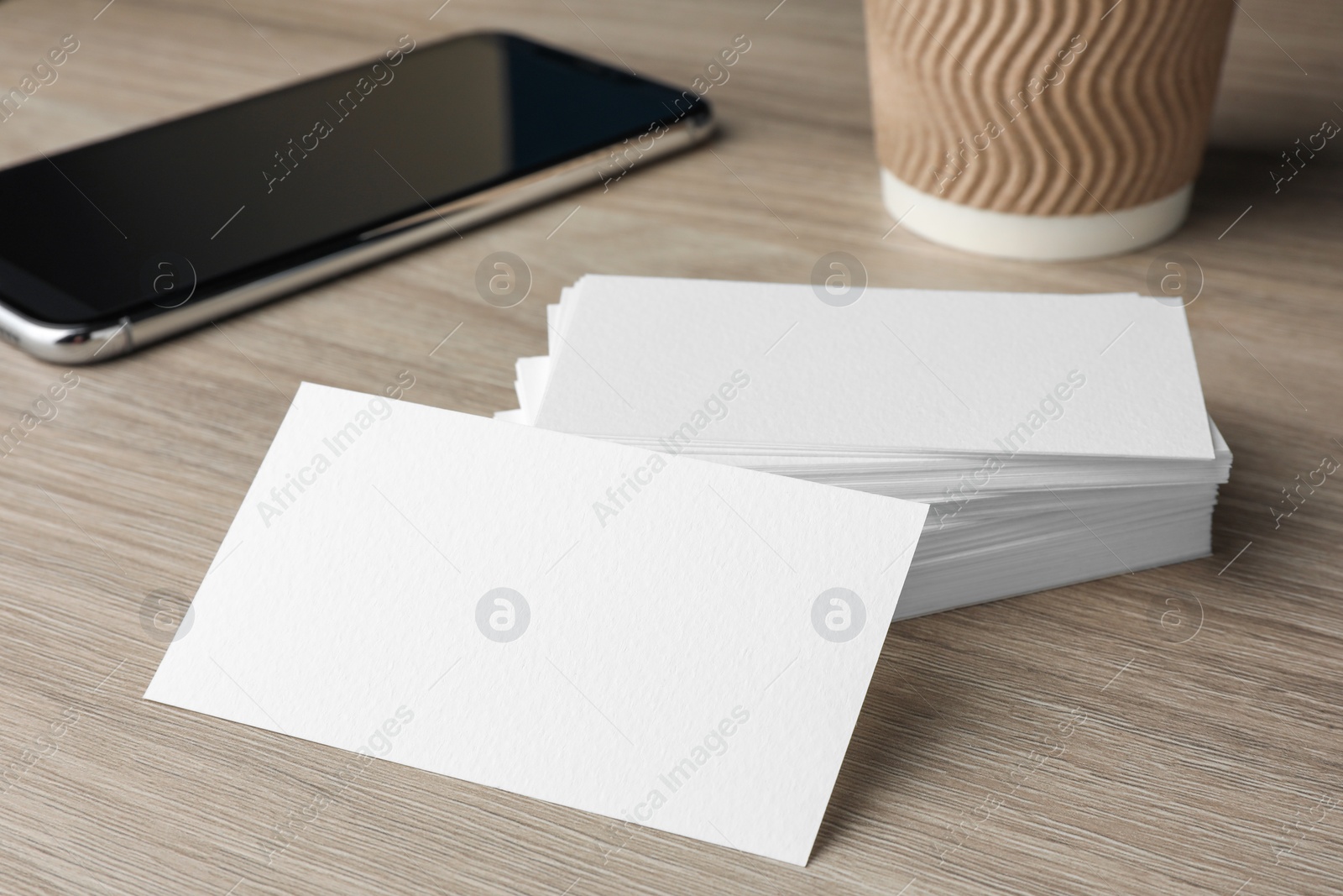 Photo of Blank business cards and smartphone on wooden table, closeup. Mockup for design