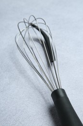 Metal whisk on gray table, closeup. Kitchen tool