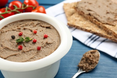 Photo of Tasty liver pate with pepper and herb on blue table, closeup. Space for text