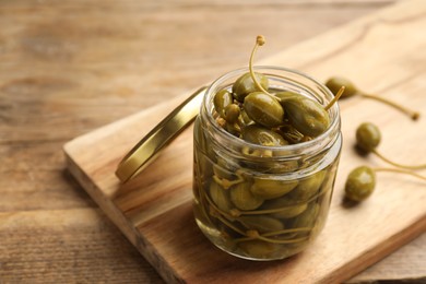 Jar of capers on wooden table, closeup. Space for text