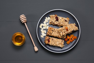 Photo of Tasty granola bars served on grey wooden table, flat lay