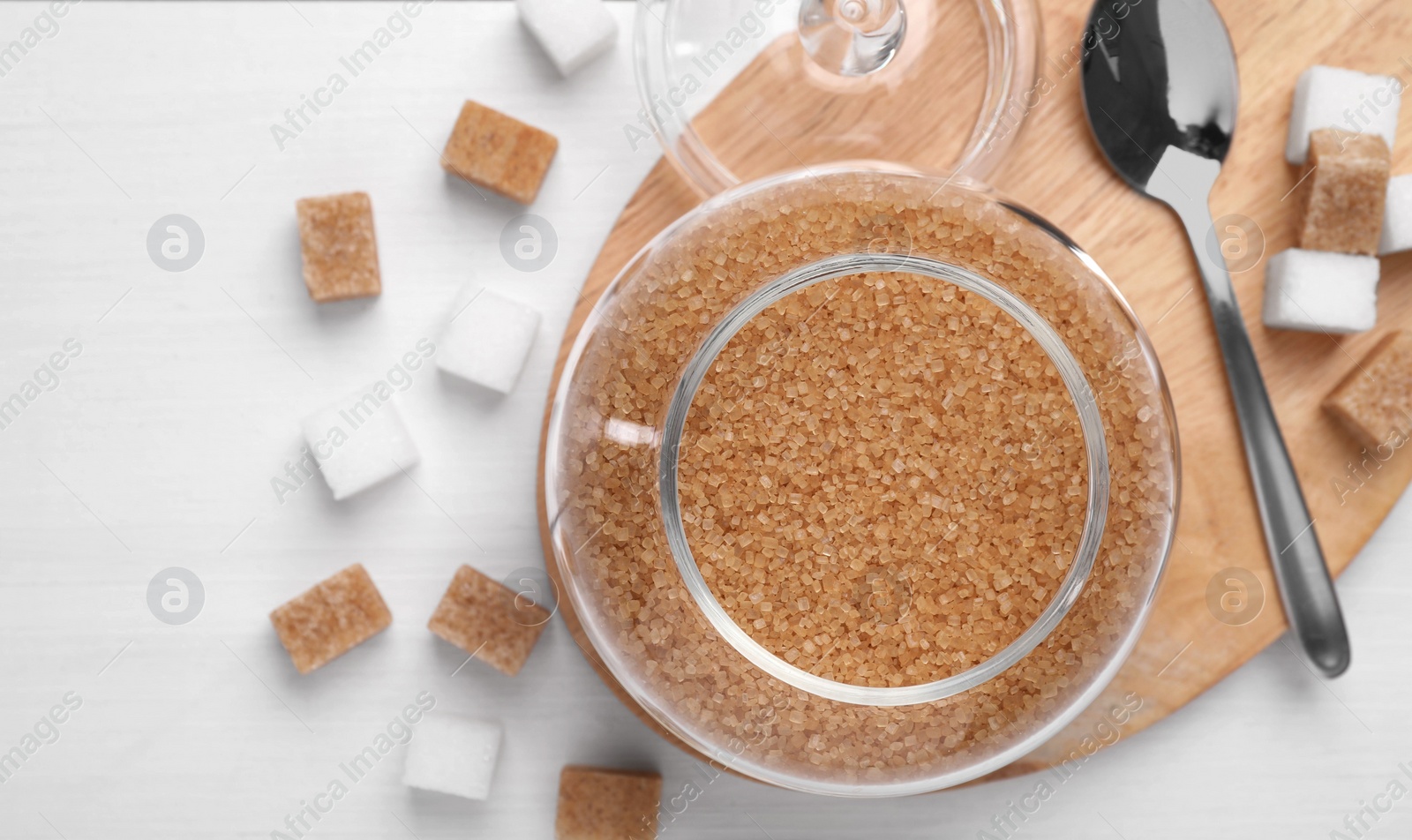 Photo of Brown sugar in jar and spoon on white table, top view