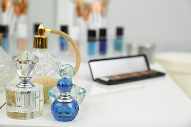 Photo of Bottle of different perfumes and makeup products on white dressing table