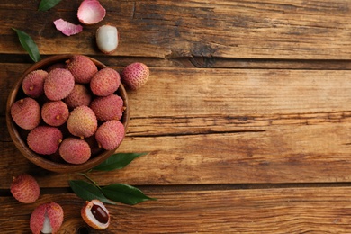 Photo of Fresh ripe lychee fruits on wooden table, flat lay. Space for text