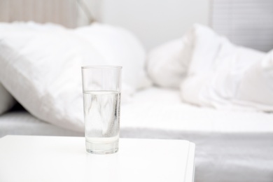 Photo of Glass of water on white nightstand in bedroom, space for text