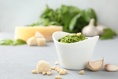 Photo of Composition with bowl of tasty pesto sauce on grey table. Space for text
