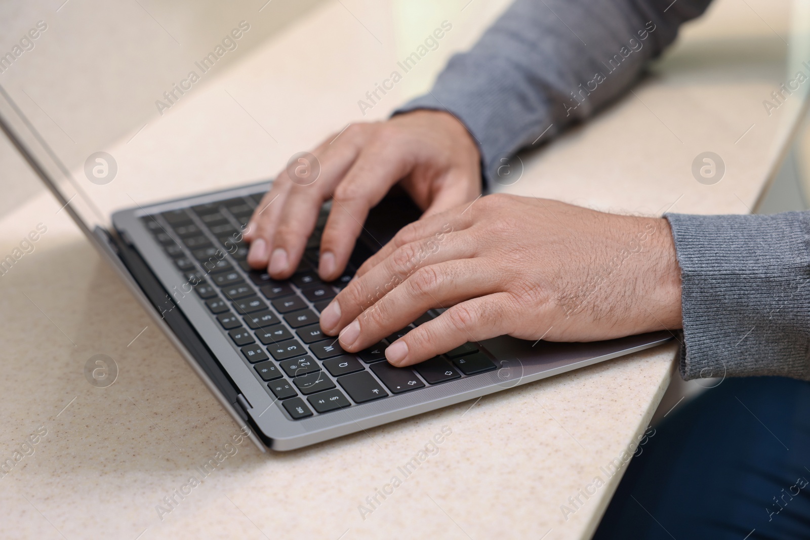 Photo of Man using laptop at beige table, closeup