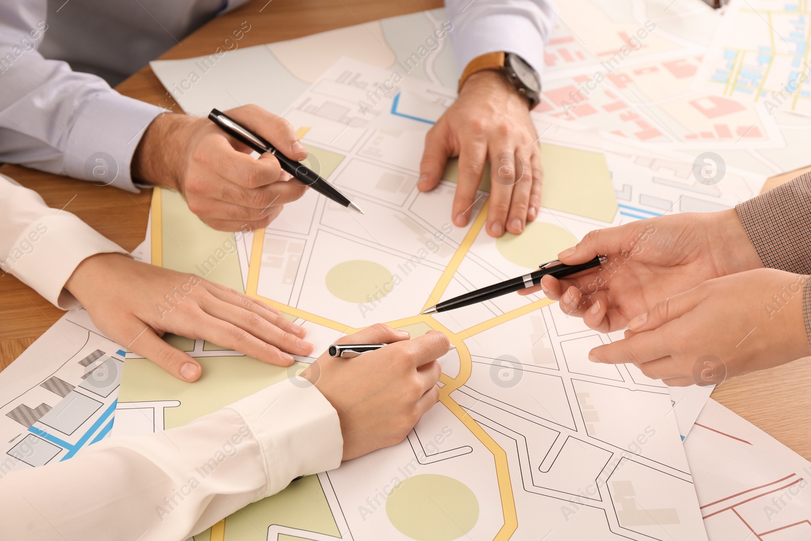 Photo of Professional cartographers working with cadastral map at table, closeup