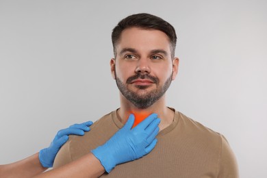 Endocrinologist examining thyroid gland of patient on light grey background, closeup