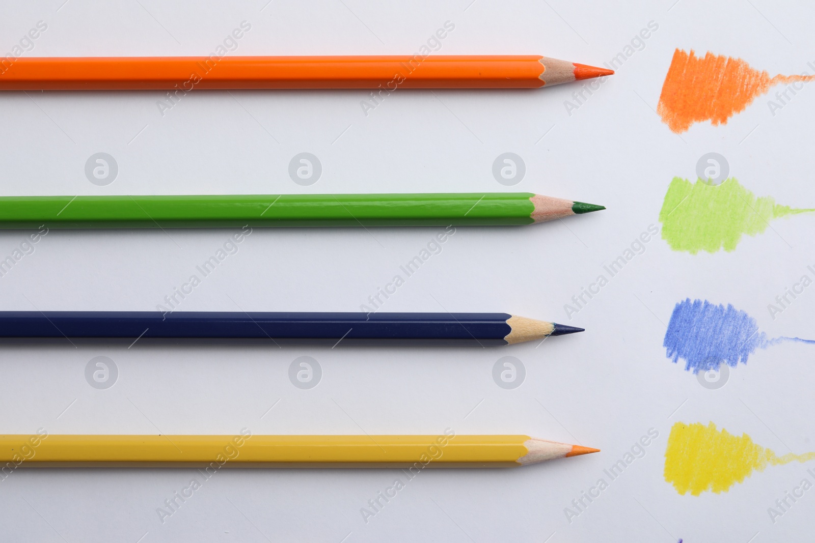 Photo of Colorful pencils with swatches on white background, top view