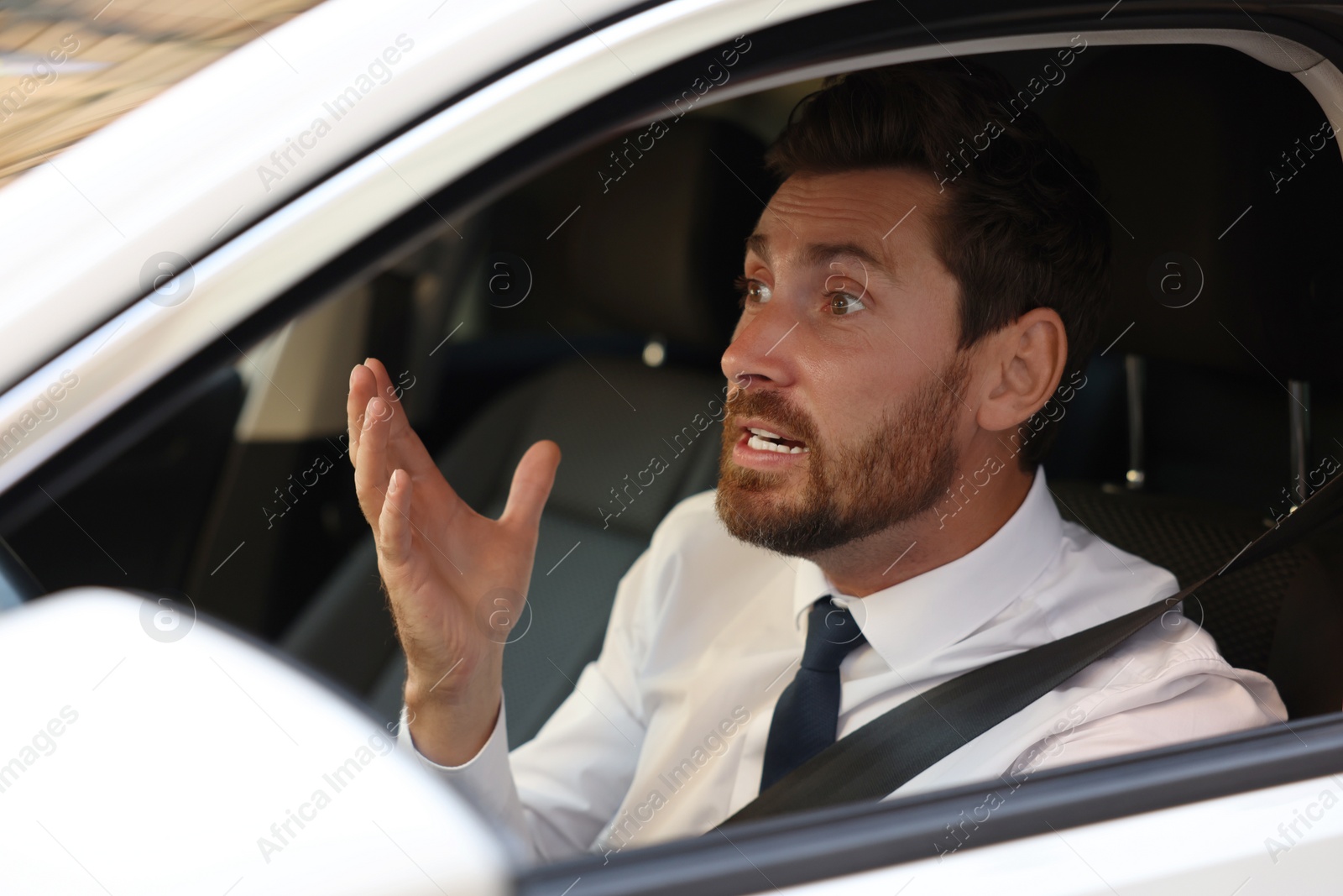 Photo of Stressed driver in his car, view from outside. Stuck in traffic jam