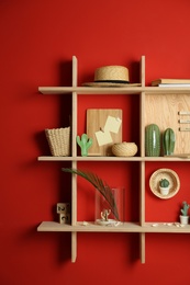 Photo of Stylish wooden shelves with decorative elements on red wall