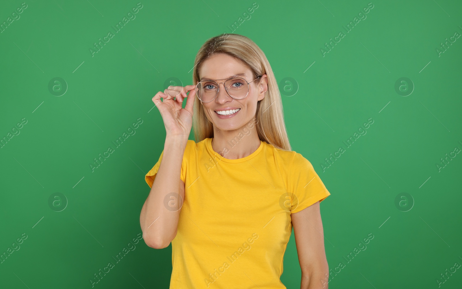 Photo of Portrait of smiling woman in stylish glasses on green background