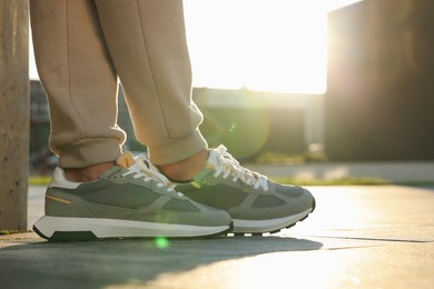 Man wearing pair of stylish sneakers outdoors, closeup