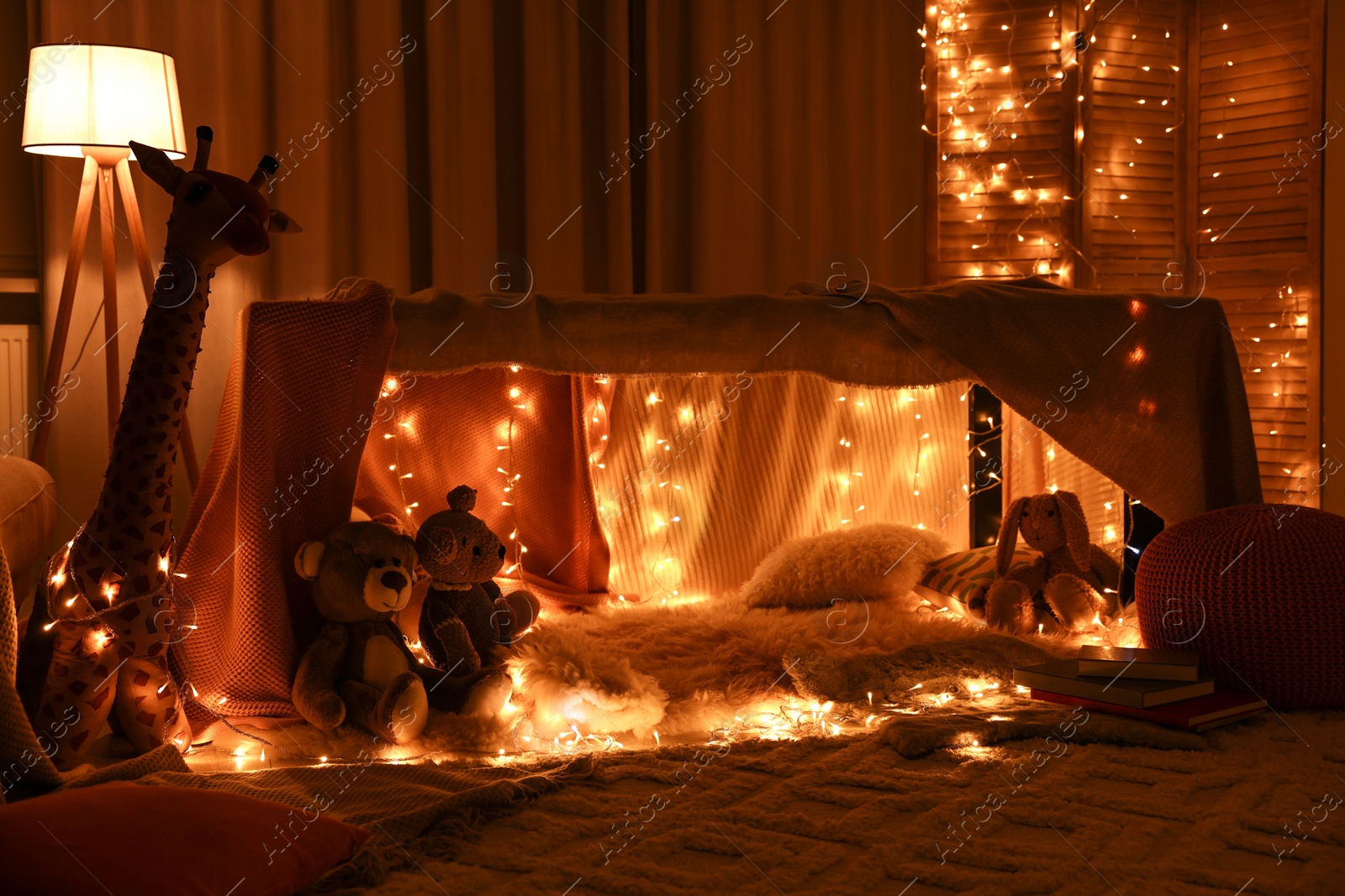 Photo of Beautiful play tent decorated with festive lights and toys at home