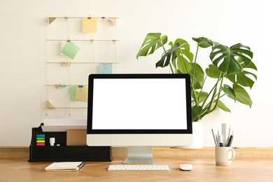 Photo of Comfortable workplace with modern computer near on table near white wall. Space for design