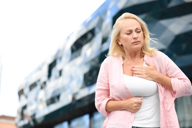 Photo of Mature woman suffering from heart attack outdoors. Space for text