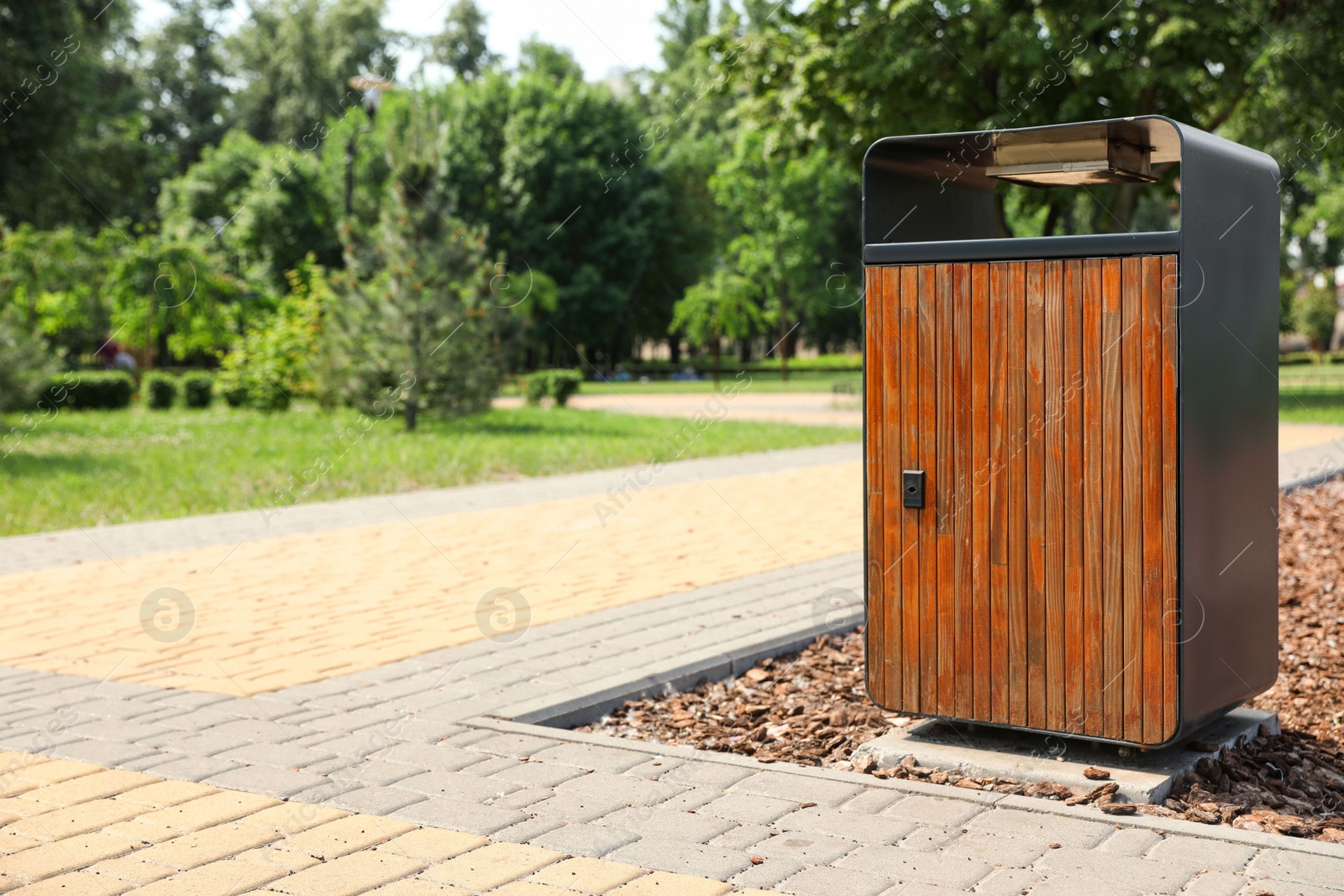Photo of Modern trash bin in park, space for text
