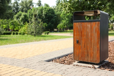 Modern trash bin in park, space for text