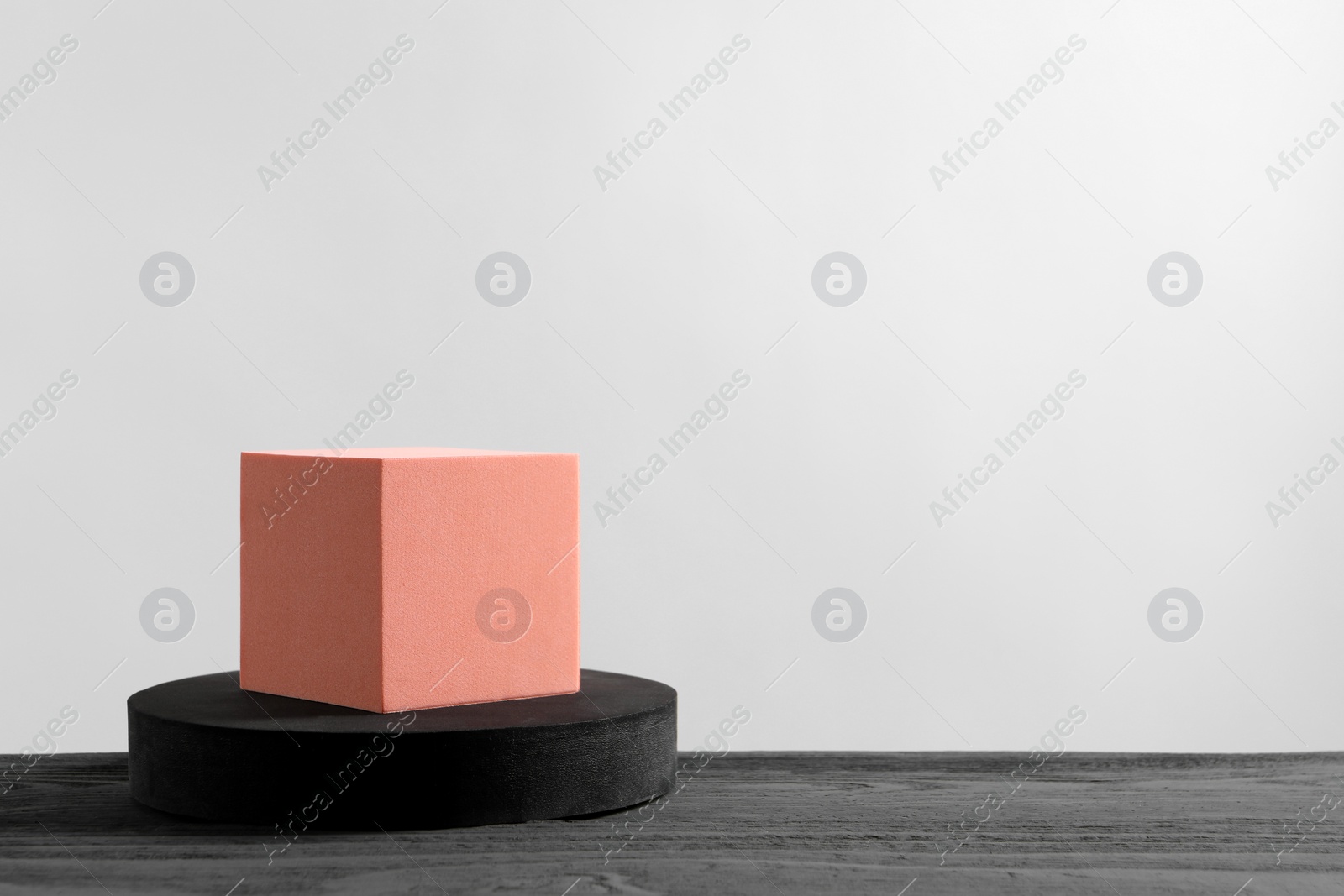 Photo of Cube and round shaped podiums on grey wooden table. Space for text