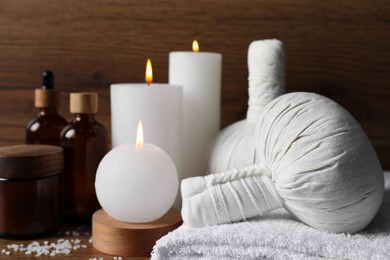 Beautiful spa composition with different care products and burning candles on wooden table, closeup. Space for text