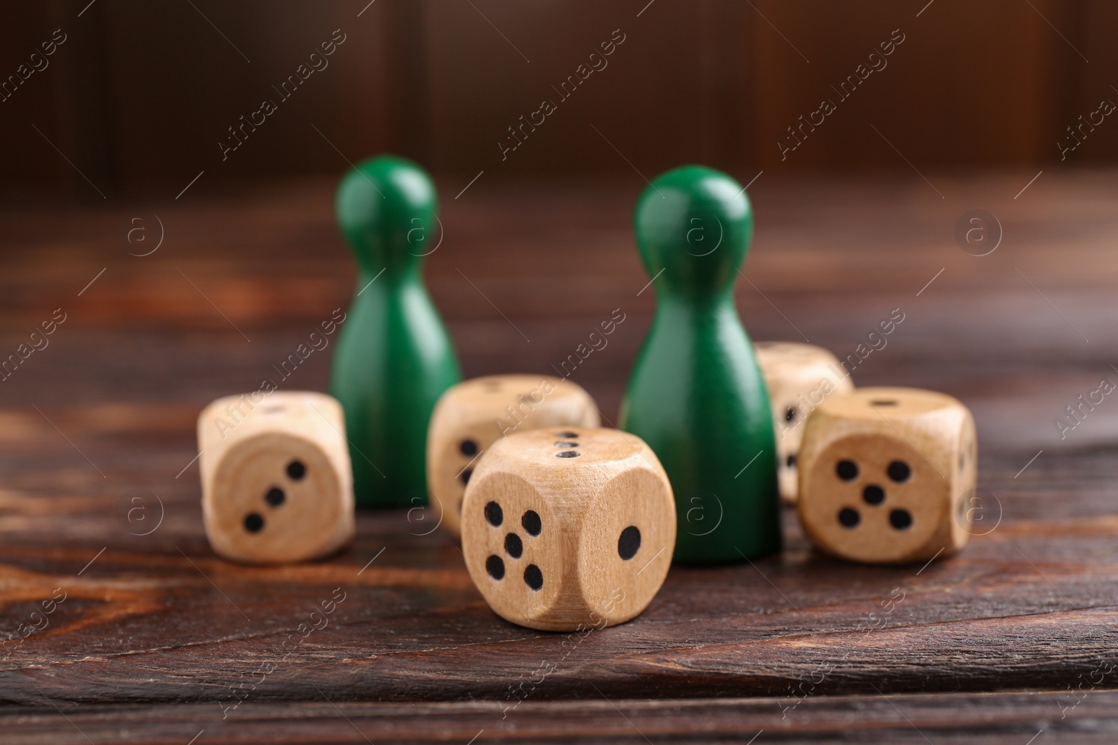 Photo of Many dices and green game pieces on wooden table, closeup