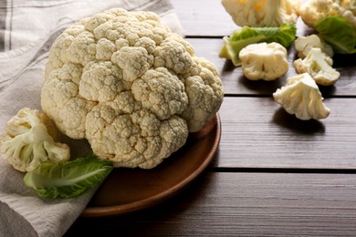 Plate with fresh raw cauliflower on wooden table. Space for text