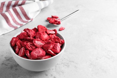 Photo of Bowl with dried strawberries on light grey table. Space for text