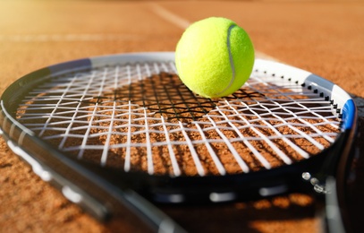 Photo of Tennis ball and racket on clay court, closeup