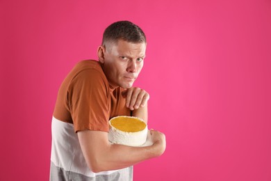 Photo of Greedy man hiding tasty cake on pink background. Space for text