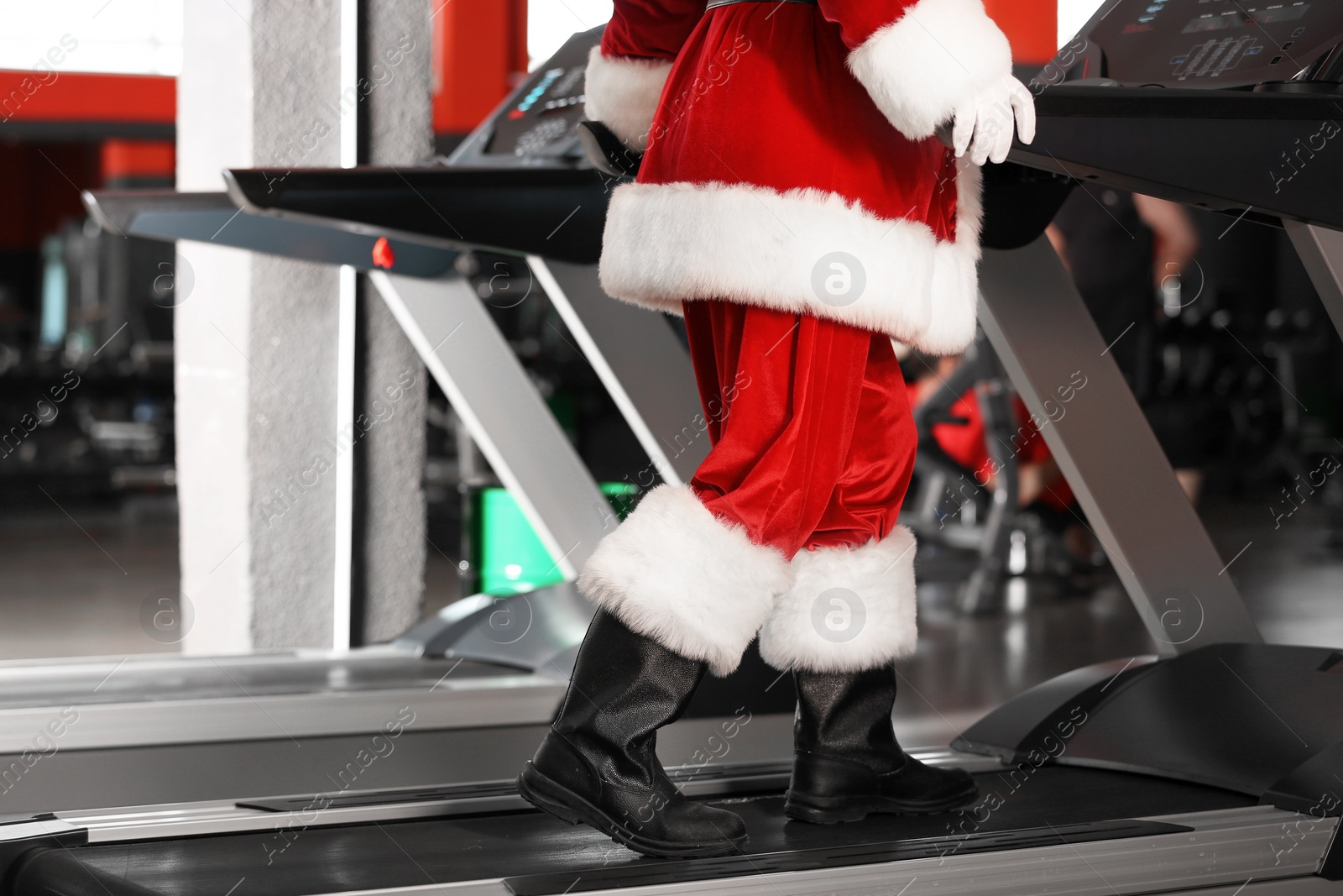 Photo of Authentic Santa Claus training on treadmill in modern gym, focus on legs