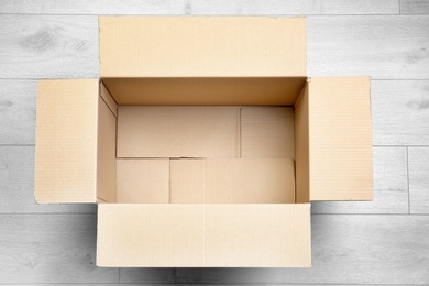 Photo of Open empty cardboard box on wooden floor