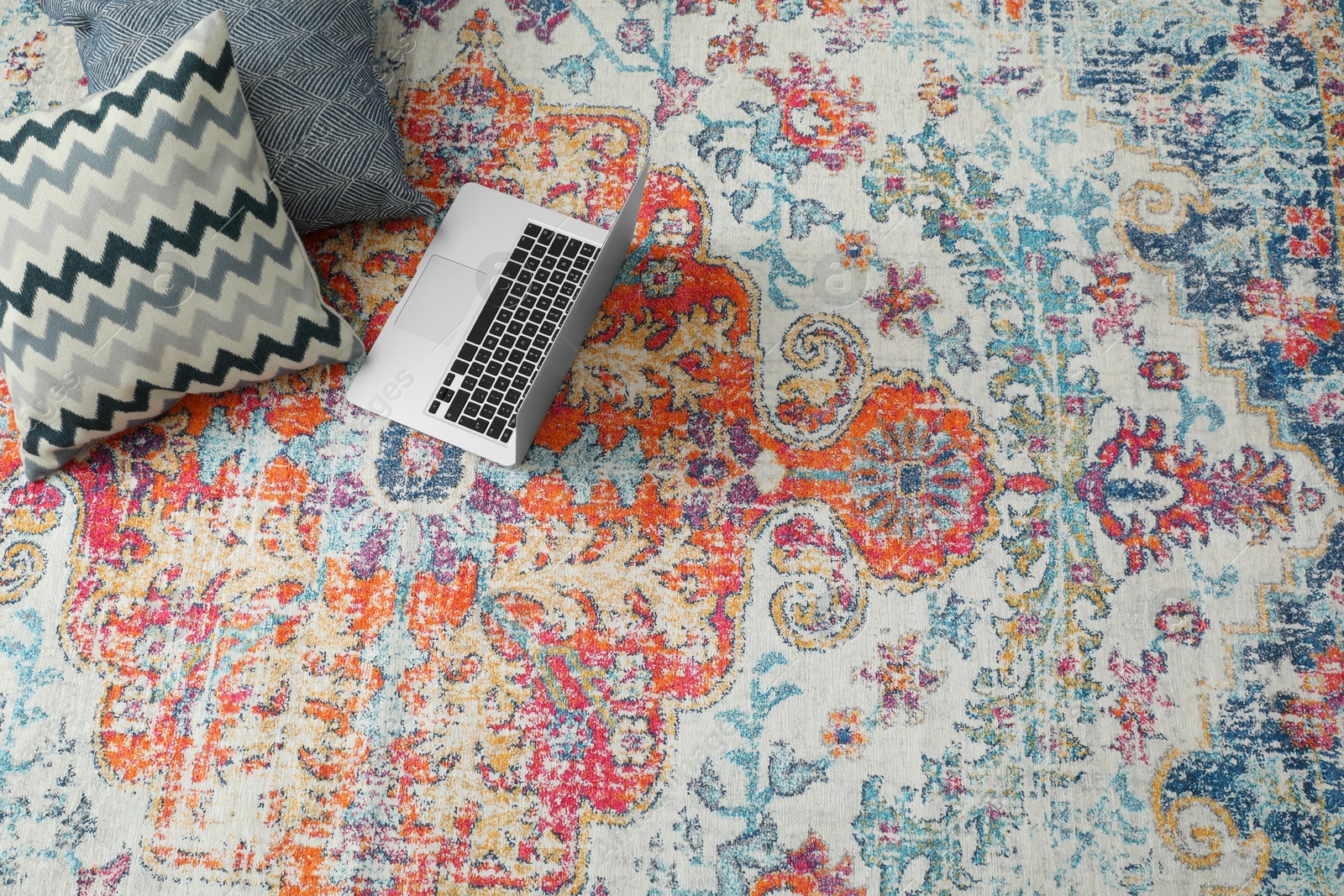 Photo of Stylish living room with beautiful carpet, laptop and pillows on floor, above view. Interior design