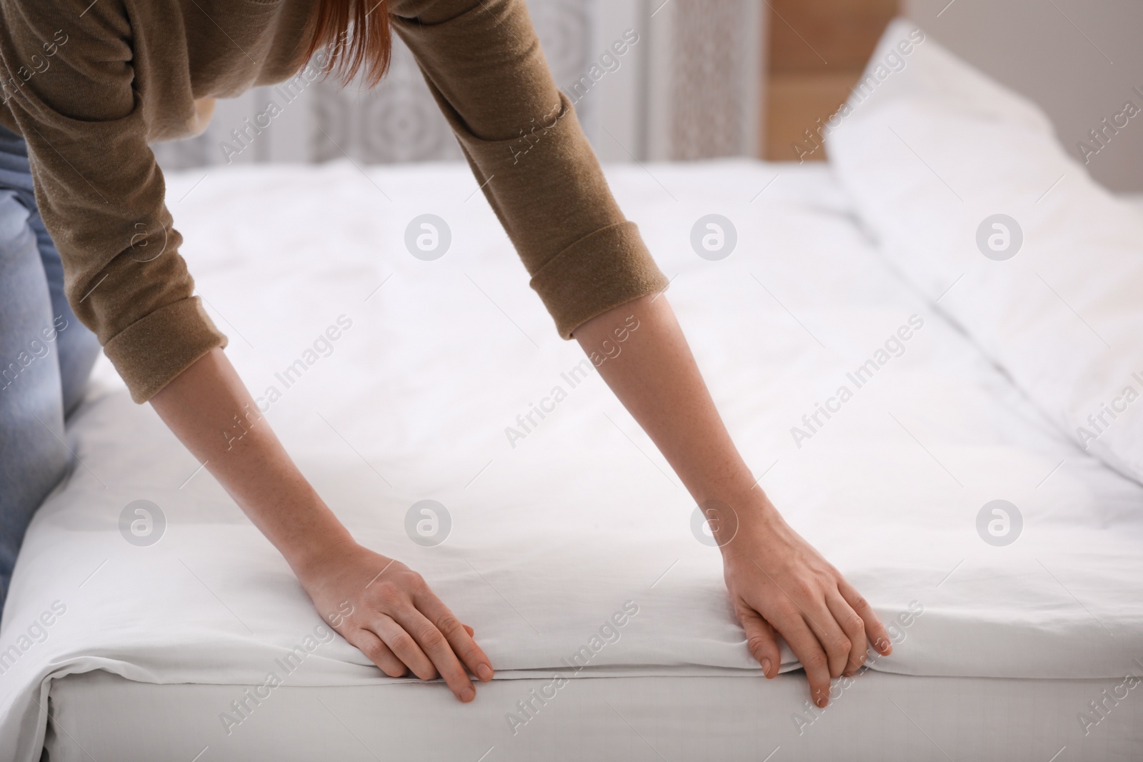 Photo of Woman making bed with stylish linens in room, closeup