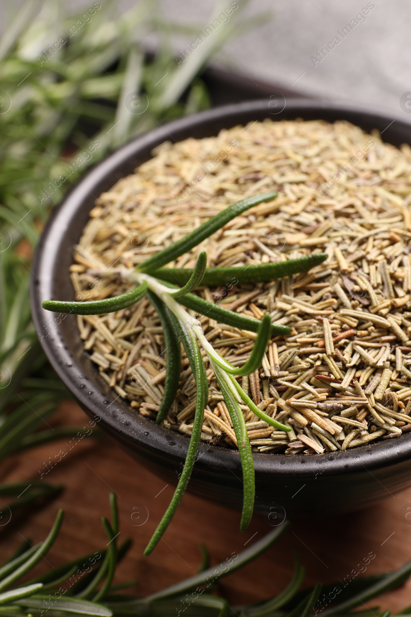 Photo of Bowl with dry and fresh rosemary on table, closeup