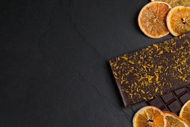 Photo of Chocolate bars with freeze dried orange on slate table, flat lay. Space for text