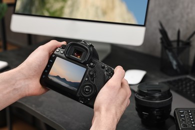 Image of Man with professional photo camera looking at shot of mountain indoors, closeup