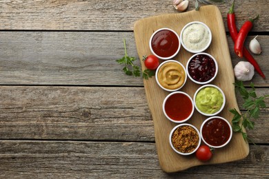 Photo of Different tasty sauces in bowls and ingredients on wooden table, top view. Space for text