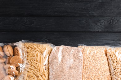 Photo of Different products on black wooden table, flat lay with space for text. Food donation