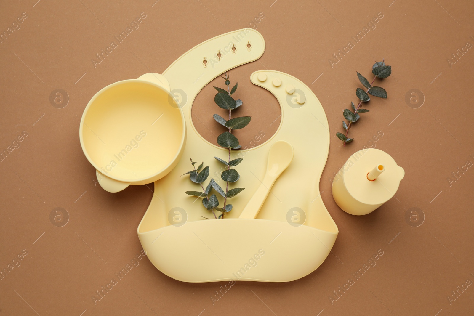 Photo of Flat lay composition with baby feeding accessories and bib on brown background