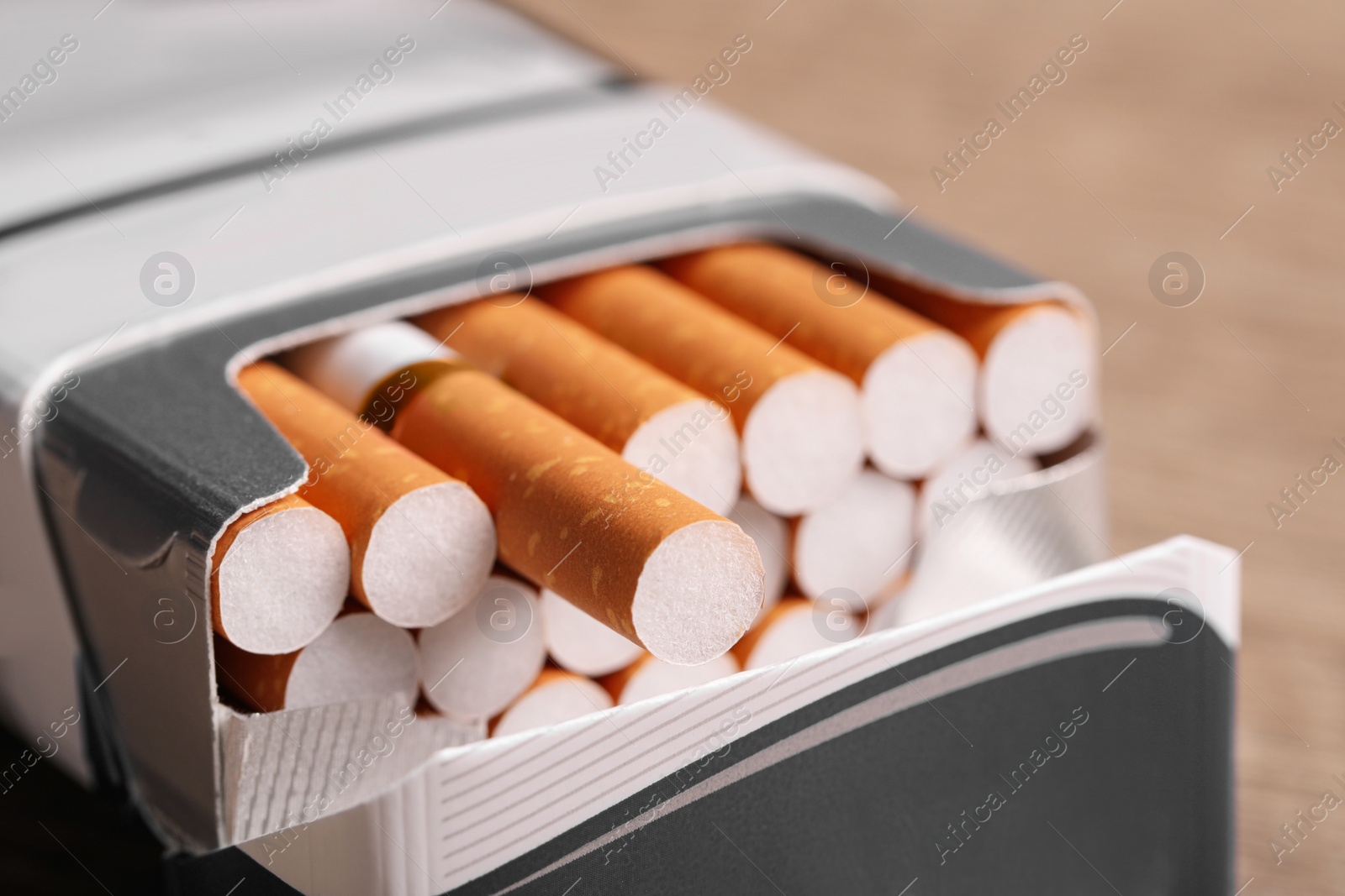 Photo of Cigarettes with orange filters in pack on table, closeup