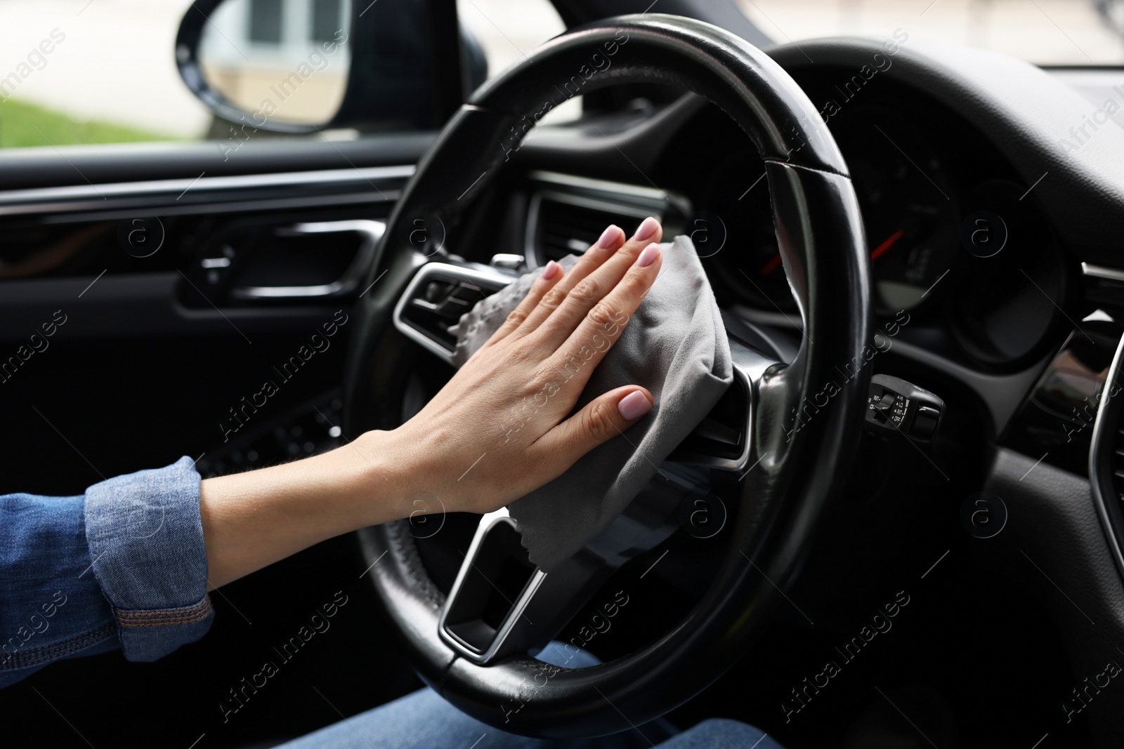 Photo of Woman wiping her modern car with rag, closeup