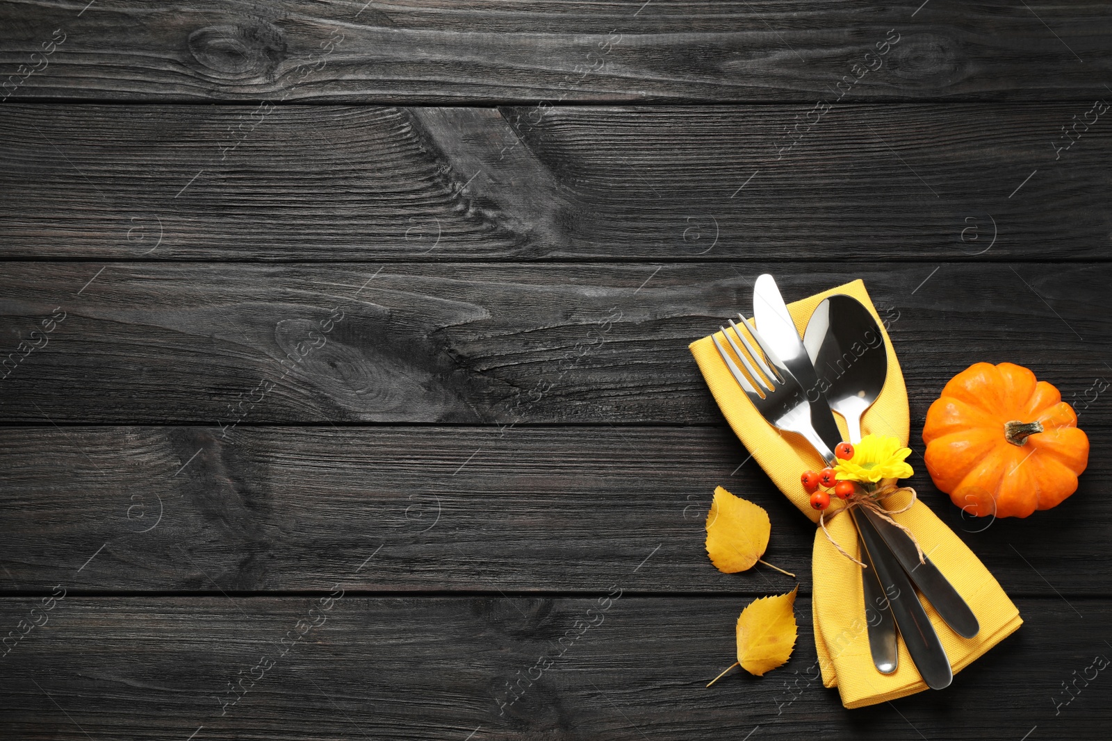 Photo of Cutlery, autumn leaves and pumpkin on black wooden table, flat lay with space for text. Thanksgiving Day