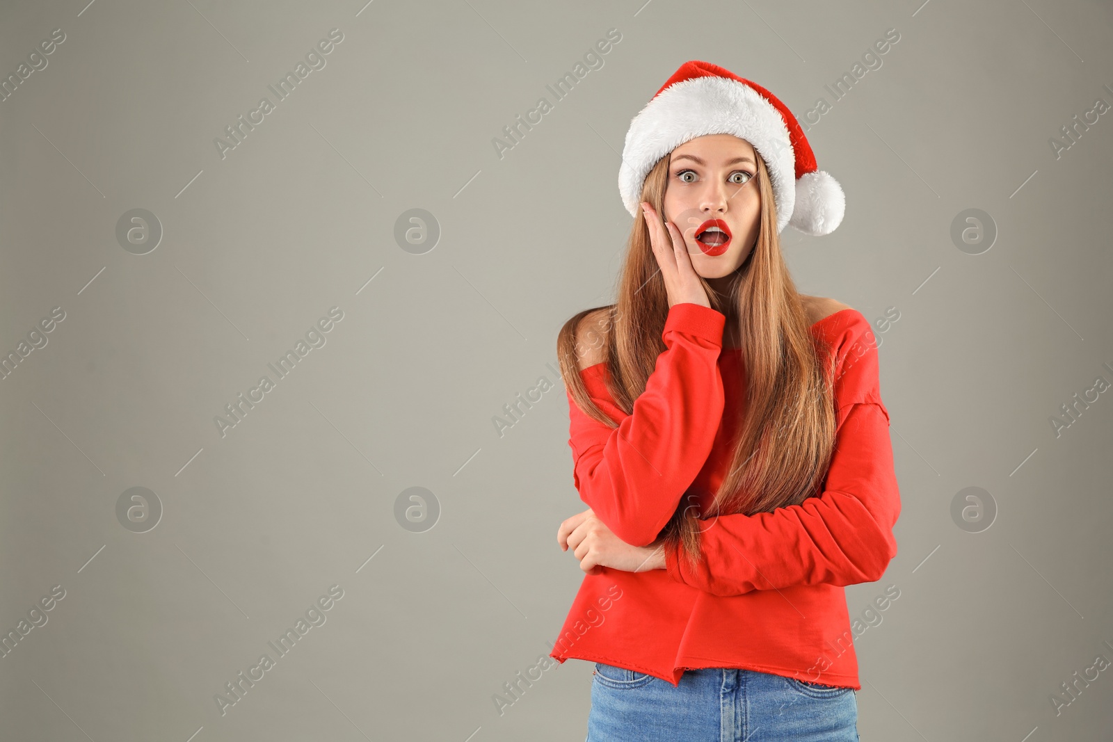 Photo of Young beautiful woman in Santa hat on grey background. Christmas celebration