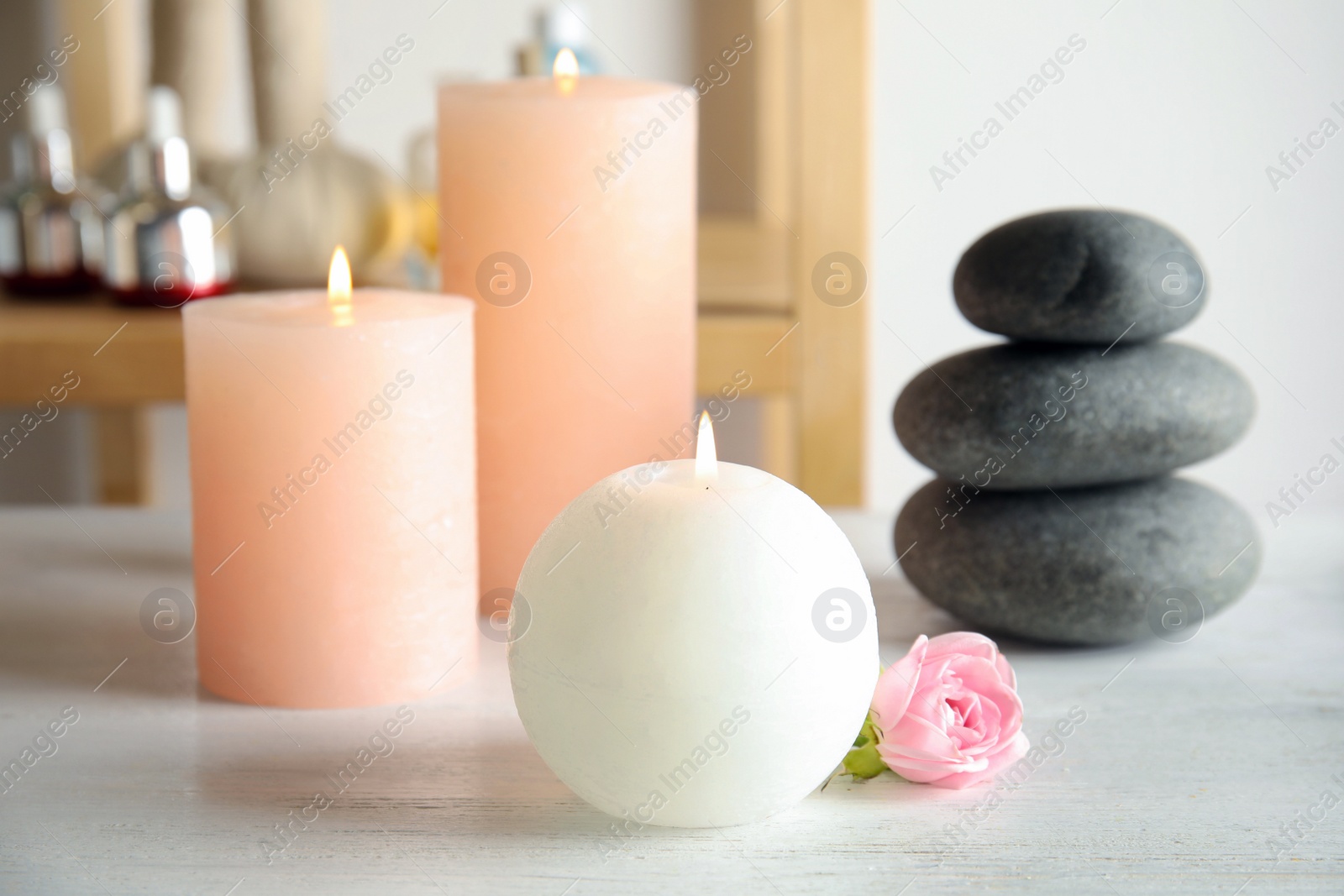 Photo of Beautiful spa composition with candles and stones on wooden table